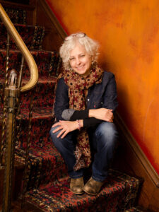 Author Kate DiCamillo sitting on the stairs and smiling.