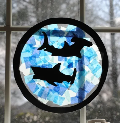 Suncatcher made from contact paper, tissue paper, and shark cut outs.